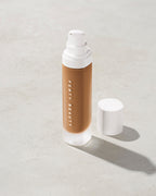 open bottle of Fenty Beauty Pro Filt'r Soft Matte Longwear Foundation with pump dispenser in shade 385 on concrete background