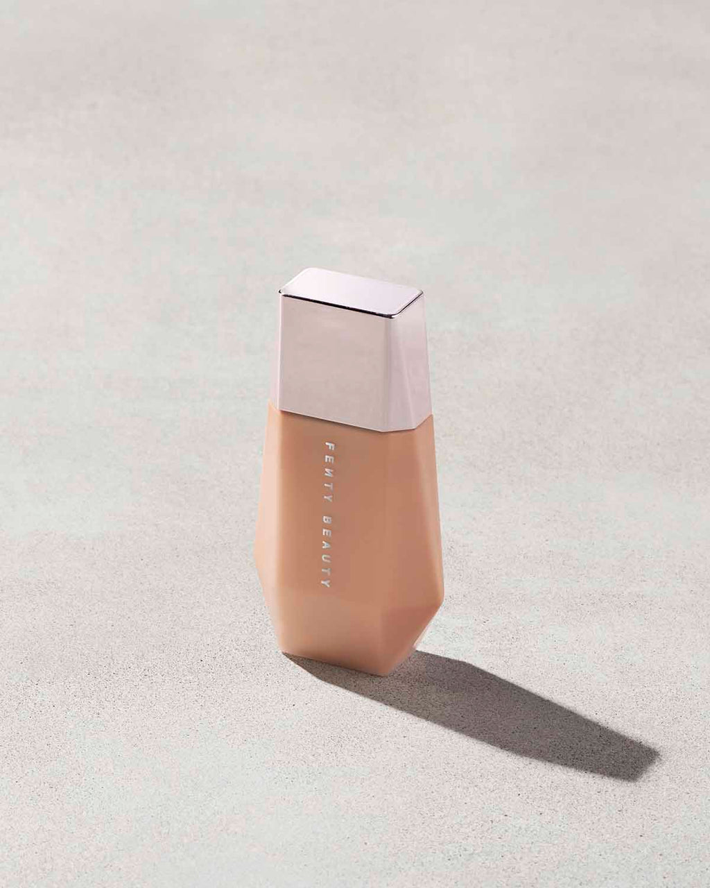 Eaze Drop’Lit All-Over Glow Enhancer shown in shade Honey Citrine on a concrete background. 